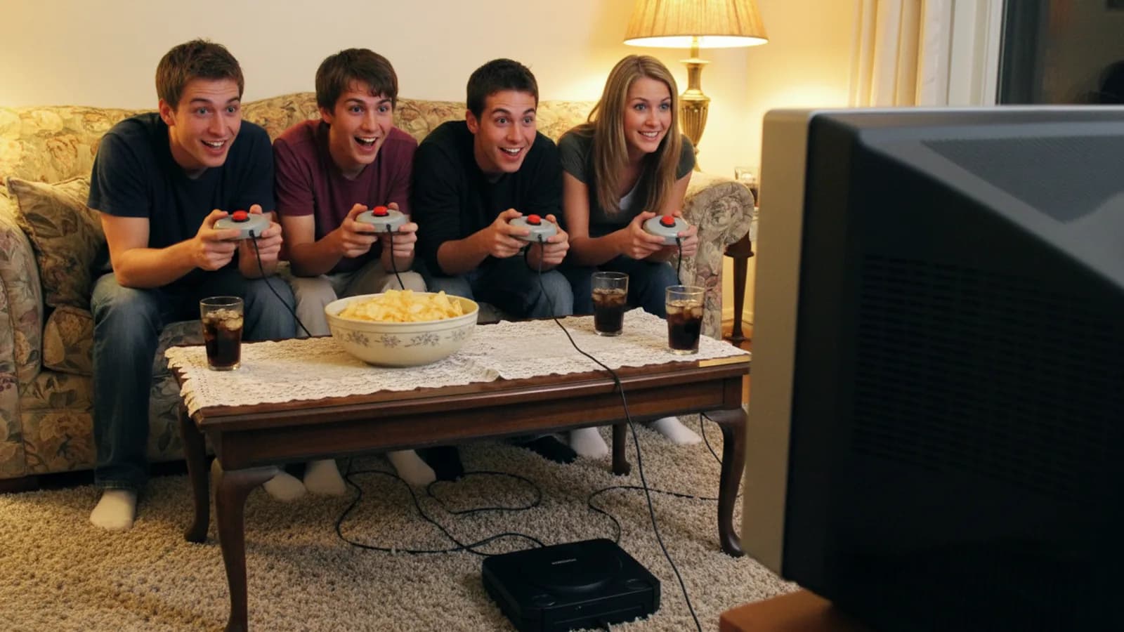 A 2000s living room: friends holding round quiz buzzers in front of a CRT television